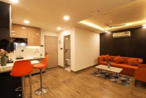 a living room with an orange couch and a kitchen at AR Suites Sohna Road in Gurgaon