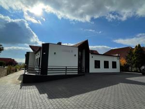 a white building with a fence in a parking lot at Jagodowa 15 in Częstochowa