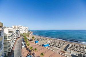 a beach with chairs and umbrellas and the ocean at Apartamento Calypso in Las Lagunas Mijas