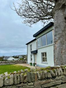 una casa blanca con un árbol delante en LAKE VIEW Luxury Apartment, en Dunfanaghy 17 fotos más
