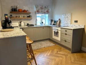 a kitchen with white cabinets and a wooden floor at LAKE VIEW Luxury Apartment in Dunfanaghy