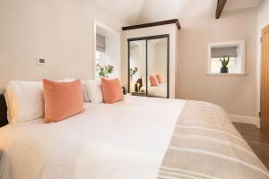 a bedroom with a large white bed with orange pillows at The Stables at West Lyham in Chatton