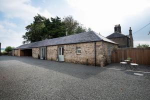 an old stone barn with a table and chairs outside at The Stables at West Lyham in Chatton