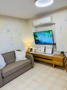 a living room with a couch and a flat screen tv at אירוח בעמק in Yesod Hamaala +5 photos