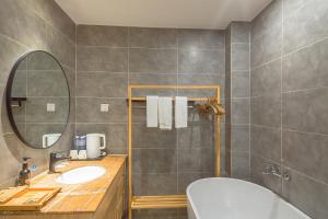 a bathroom with a sink and a mirror and a tub at Heinemann Hotel courtyard or terrace king room A108 with a jacuzzi and a local in Baoguosi