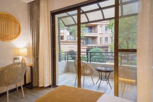 a bedroom with a balcony with a table and chairs at Heinemann Hotel courtyard or terrace king room A108 with a jacuzzi and a local in Baoguosi +6 photos
