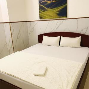 a bed with a wooden head board with a white mattress at Du Thuyền 2 Hotel Hồ Chí Minh in Ho Chi Minh City