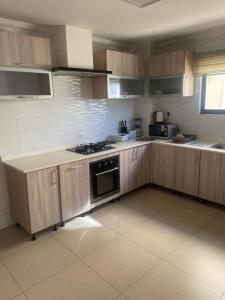cocina con armarios de madera y fogones en The Spaggy family villa, en Accra