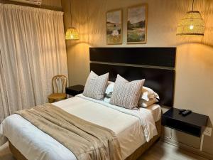 a bedroom with a large bed with white sheets and pillows at The Suburban Guest House in Bloemfontein