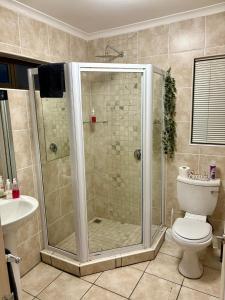 a bathroom with a shower with a toilet and a sink at The Suburban Guest House in Bloemfontein +63 photos