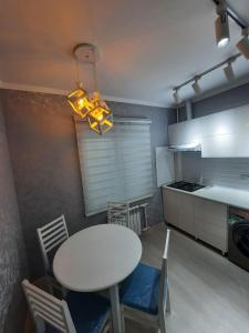 Center-Train Station-Airport في Toshkent-Passajir Bekati: مطبخ مع طاولة وكراسي بيضاء وإضاءة مساعدة