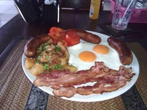 a plate of breakfast food with eggs sausage and tomatoes at Hong Ky Boutique Hotel in Diện Biên Phủ