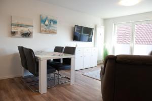 a living room with a table and chairs and a tv at Deichnähe B in Norddeich