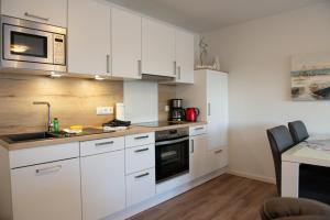 a kitchen with white cabinets and a sink and a table at Deichnähe B in Norddeich