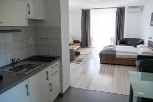 a kitchen with a sink and a bedroom with a bed at F&M Apartman in Egerszalók