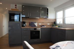una cucina con armadi grigi e piano cottura. di Deichstübchen oben a Norddeich
