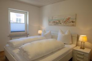 two white beds in a room with a window at Deichnähe F in Norddeich