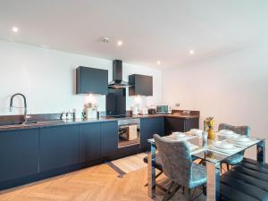 a kitchen with blue cabinets and a table with chairs at Stylish 2BR City-Centre Apart Near LGI & Leeds Uni Sleeps 6 in Leeds