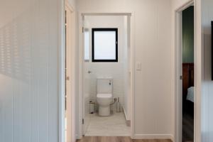 ein weißes Bad mit einem WC und einem Fenster in der Unterkunft Tuckeroo Cottages - Rosella Cottage in Maroon