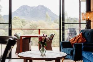 ein Wohnzimmer mit einer Vase mit Blumen auf einem Tisch in der Unterkunft Tuckeroo Cottages - Rosella Cottage in Maroon