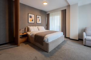 a hotel room with a bed and a chair at Five Apartments in Pristina
