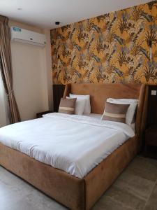 Una cama grande en un dormitorio con papel pintado floral. en Linaa, en Libreville