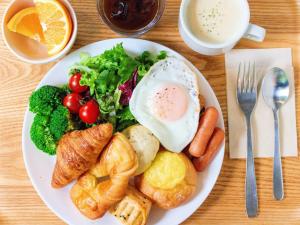 a white plate of food with an egg and vegetables at HOTEL RELIEF Sapporo Susukino in Sapporo