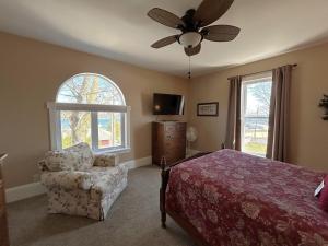 a bedroom with a bed and a chair and a ceiling fan at Lady Mary Angeline in Saint Ignace