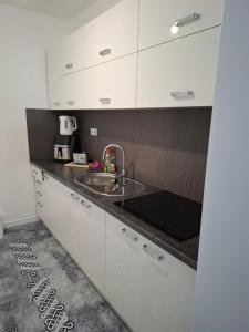 a kitchen with white cabinets and a sink at Apartman Ditka in Bihać
