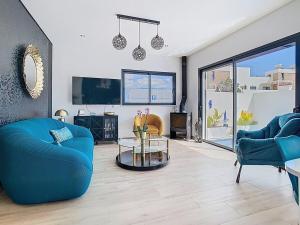 a living room with two blue chairs and a tv at Casa Launa Fuseta in Fuzeta