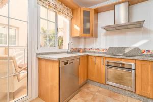Una cocina con gabinetes de madera y electrodomésticos de acero inoxidable. en Ático con piscina en Nerja centro, en Nerja