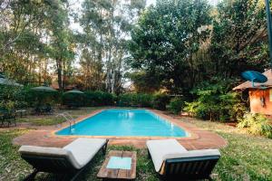 a swimming pool in a yard with two chairs next to it at Octagon Lodge in Karatu