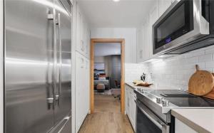 a kitchen with a stainless steel refrigerator and white cabinets at Waterfront Three-Bedroom Condo with Great Views in Naples