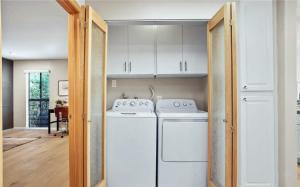 a kitchen with white cabinets and a washer and dryer at Waterfront Three-Bedroom Condo with Great Views in Naples