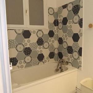 een badkamer met een bad en een tegelwand bij Les jours heureux in Gravelines