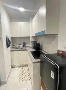 a small kitchen with white cabinets and a black refrigerator at Homestay,Gaming in Shah Alam