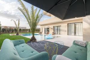 a living room with two blue chairs and a pool at Villa Sofya - Roche Bobois Design & HD Wifi in Marrakesh
