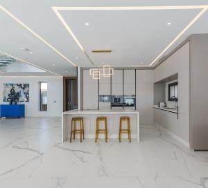 a kitchen with a white counter and two stools at Villa Sofya - Roche Bobois Design & HD Wifi in Marrakesh