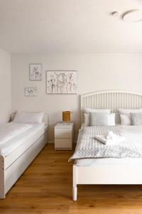 2 Betten in einem Schlafzimmer mit weißen Wänden und Holzböden in der Unterkunft Ferienwohnung Kleiner Fuchs - für Familien mit Babys eingerichtet in Höchenschwand