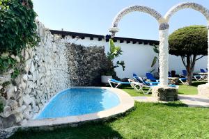 a swimming pool in a yard next to a stone wall at Alojamientos Nacarum in El Palmar