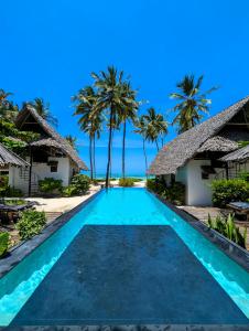 a swimming pool at a resort with palm trees at Savera Beach Houses in Jambiani