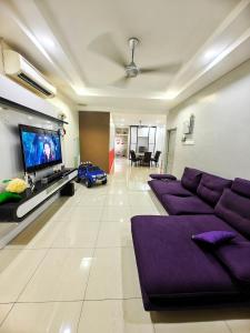 un salon avec des canapés violets et une télévision à écran plat dans l'établissement Fun Fun Stay Tangkak by GX Homestay, à Tangkak