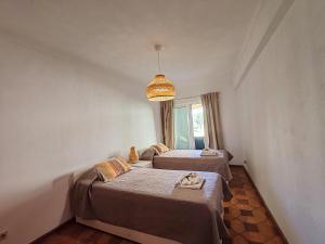 a bedroom with two beds and a chandelier at 61 Casa Pitta Manau - Casas & Papéis in Porches +20 photos