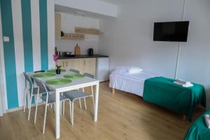 a small room with a table and chairs and a bed at Apartamenty Poddąbek- basen kryty, sauna, animacje dla dzieci , małpi gaj, baseny na dachu in Poddąbie