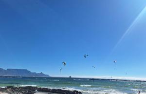 un grupo de personas volando cometas sobre el océano en Foam House, en Bloubergstrand