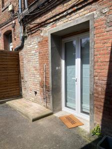 an open door to a brick building with a glass door at Duplex quartier calme et parking gratuit in Amiens