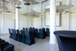 a conference room with black chairs and chandeliers at Pałac Domaniowski in Wieniawa