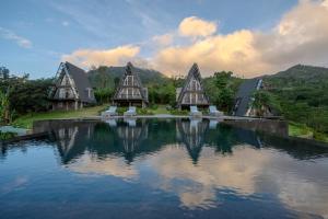 a building with a reflection in the water at Luxury Villas in Munduk at walking distance to Tamblingan Lake in Munduk