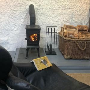 a book sitting on a couch next to a stove at Raven Cottage in Rhiconich