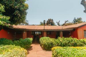 una casa roja con arbustos delante en Jameson House, en Karatu